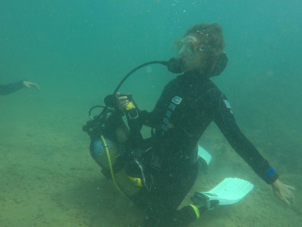 Buceadora de rodillas sobre fondo marino